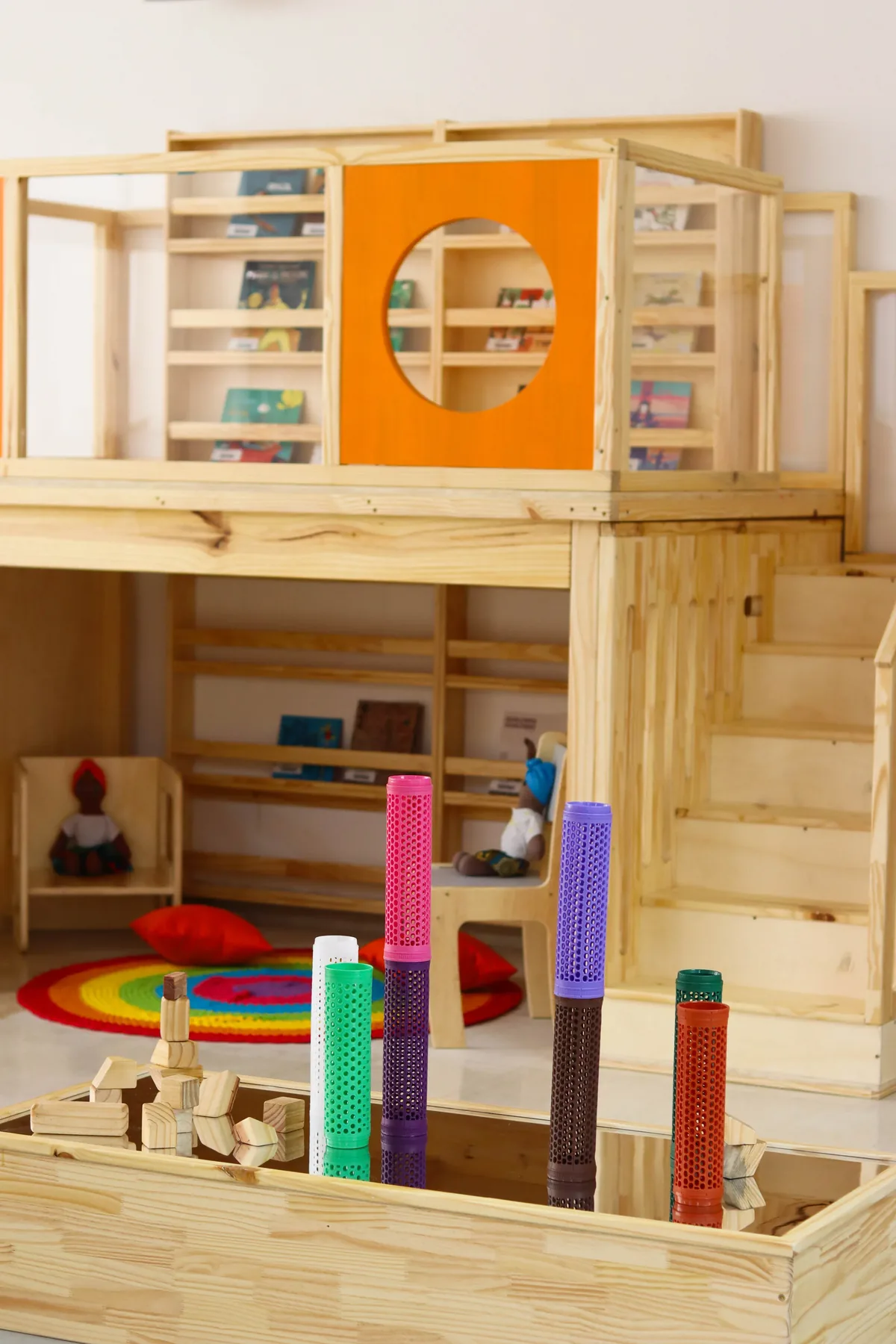 Brinquedoteca da unidade Higienópolis, com estante de livros, escada de madeira e tapete colorido